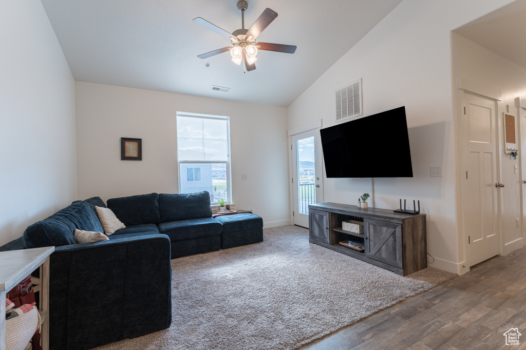 Living room with a ceiling fan, vaulted ceiling, wood finished floors, and baseboards