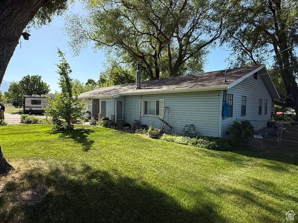 Back of house with a yard and a shingled roof