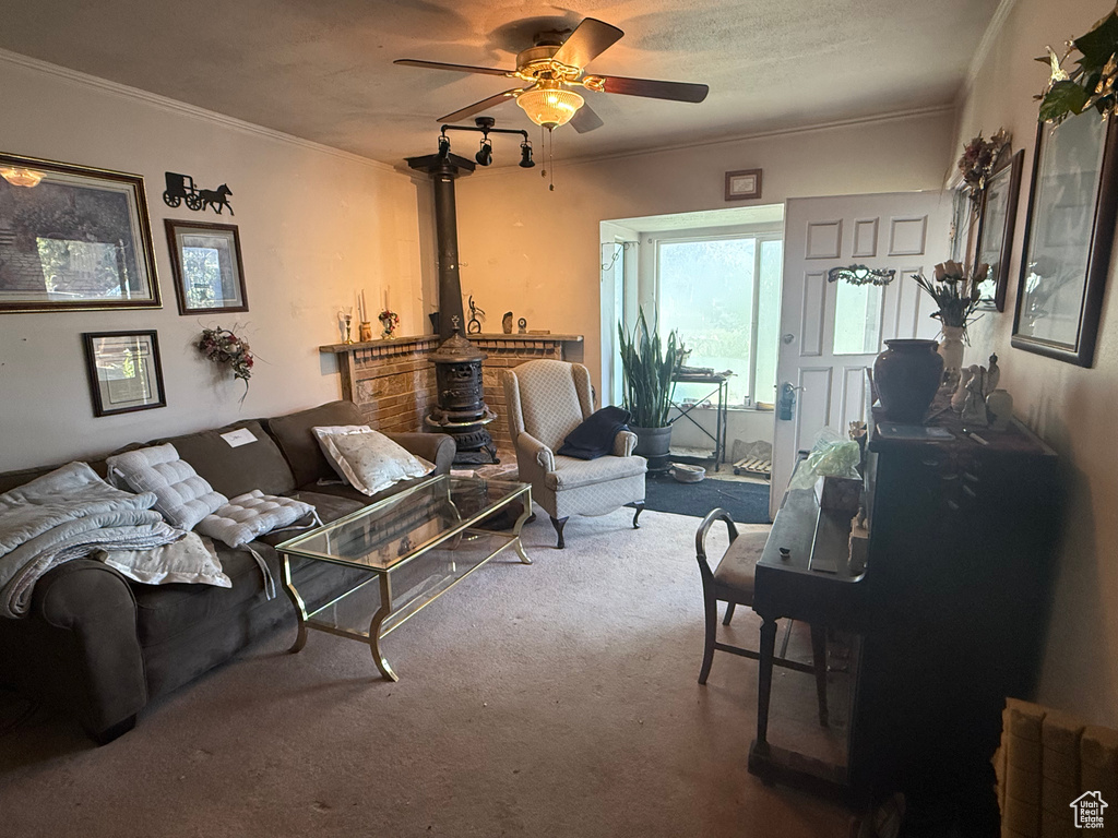 Carpeted living area featuring a ceiling fan, ornamental molding, and a wood stove