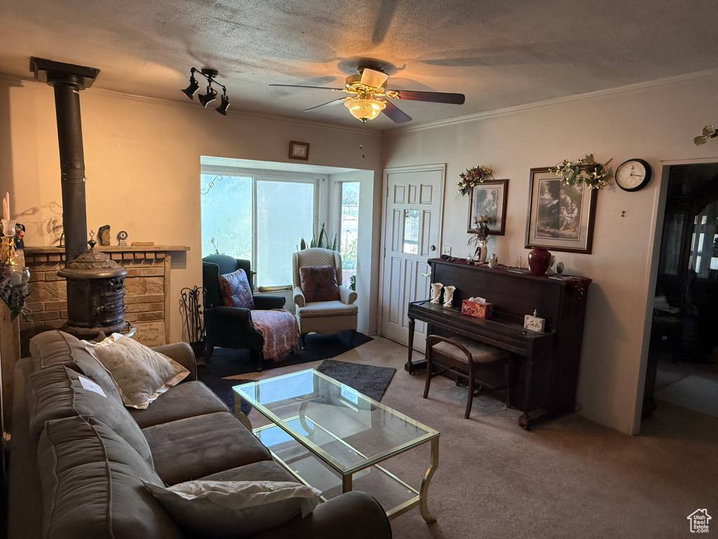 Carpeted living area featuring a ceiling fan, a wood stove, and crown molding
