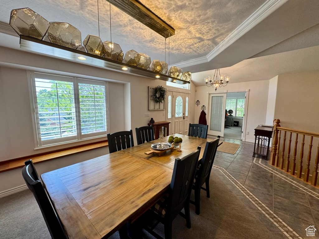 Dining space with a tray ceiling, a chandelier, baseboards, tile patterned floors, and crown molding