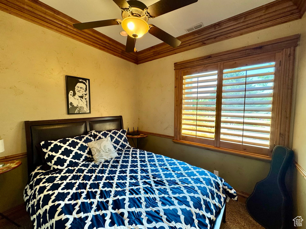 Carpeted bedroom with crown molding and ceiling fan