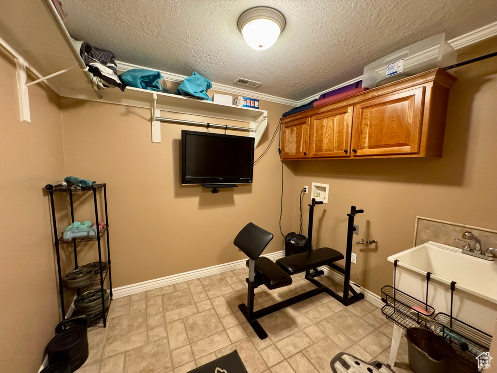 Exercise area featuring baseboards, a textured ceiling, and crown molding