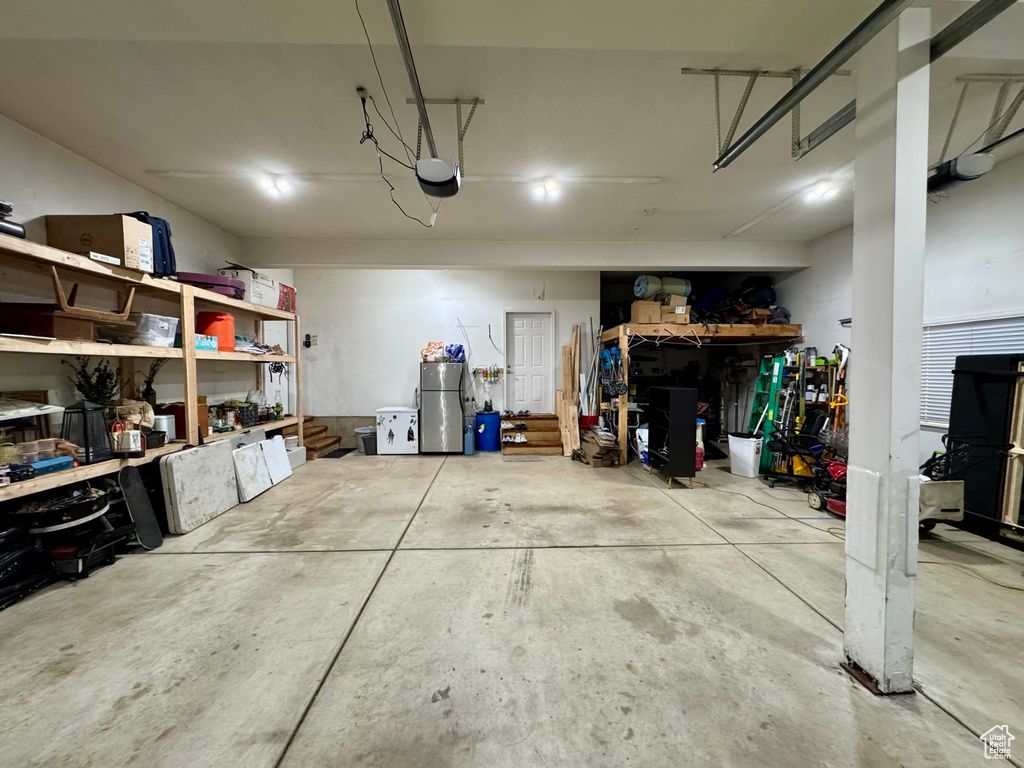 Garage featuring a garage door opener, freestanding refrigerator, and a workshop area