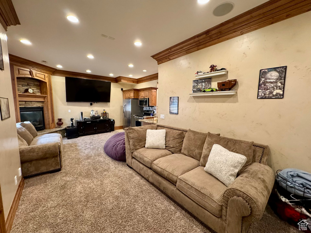 Living area with ornamental molding, carpet flooring, recessed lighting, and a fireplace