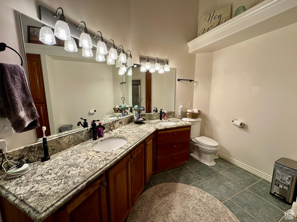 Full bathroom with toilet, vanity, baseboards, and tile patterned flooring