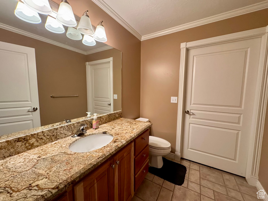 Bathroom with vanity, crown molding, toilet, baseboards, and tile patterned flooring