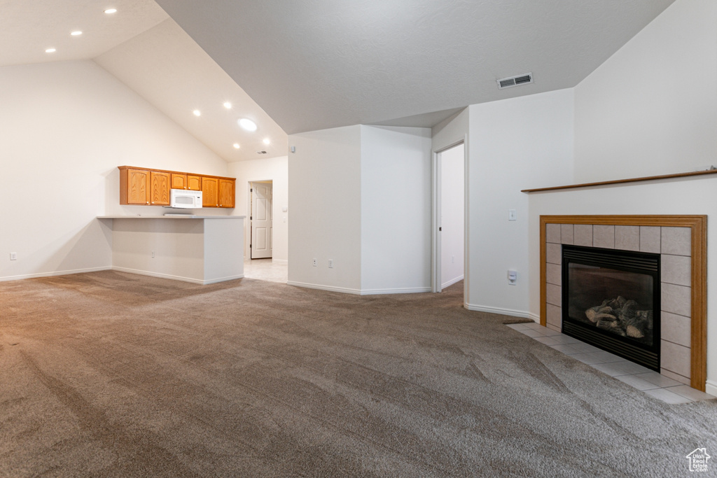 Unfurnished living room featuring light colored carpet, recessed lighting, lofted ceiling, a tile fireplace, and baseboards