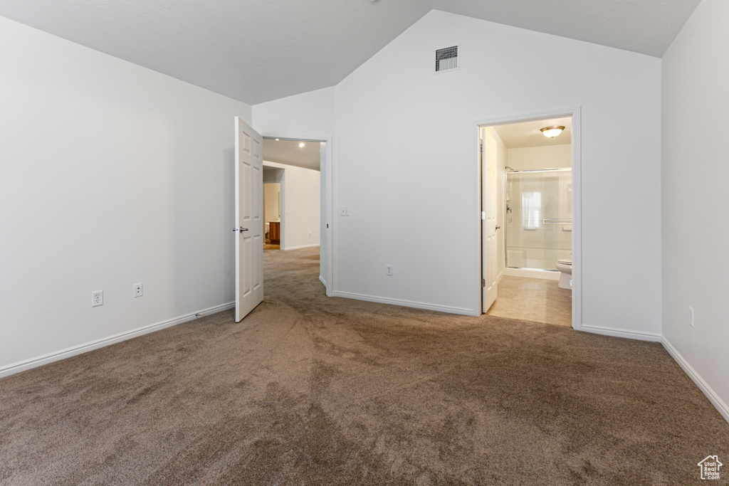Unfurnished bedroom with carpet floors, vaulted ceiling, baseboards, and ensuite bathroom