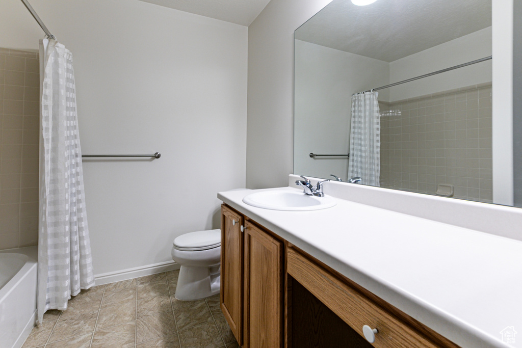 Full bathroom featuring toilet, vanity, shower / bathtub combination with curtain, and baseboards