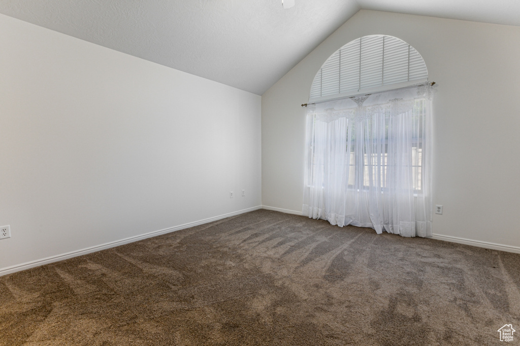 Carpeted spare room featuring lofted ceiling and baseboards