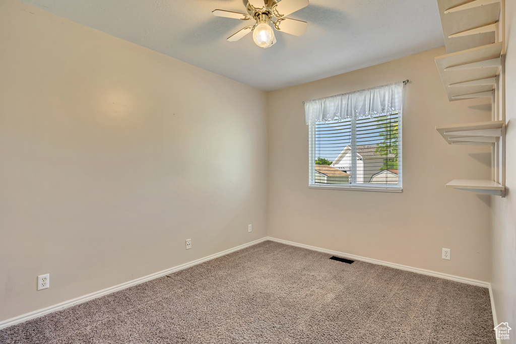 Carpeted empty room featuring a ceiling fan and baseboards