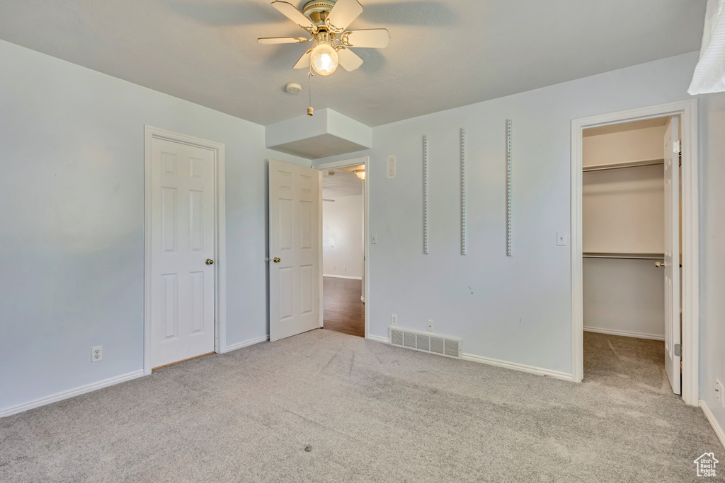 Unfurnished bedroom featuring carpet floors, a walk in closet, and baseboards