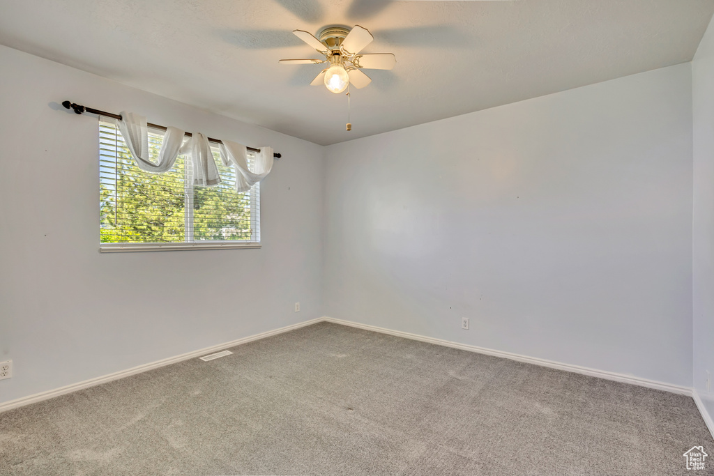 Spare room featuring carpet flooring, ceiling fan, and baseboards
