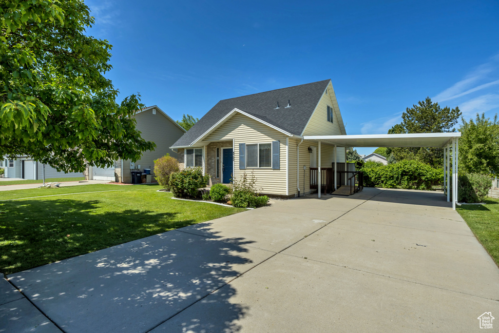 View of front facade featuring concrete driveway, a front yard, an attached carport, and roof with shingles