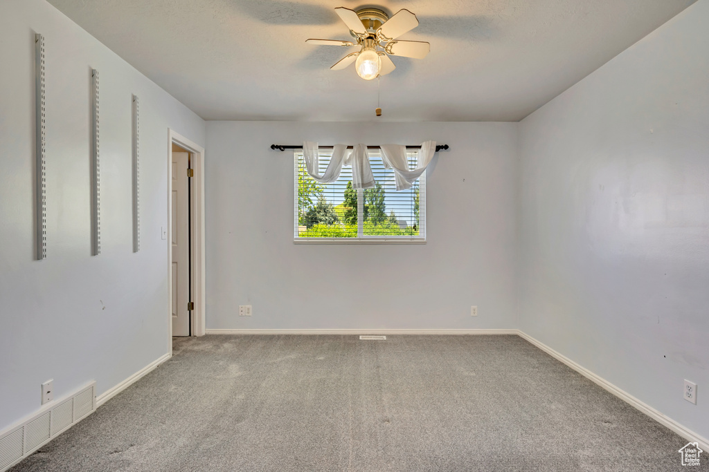 Empty room featuring carpet floors, baseboards, and a ceiling fan