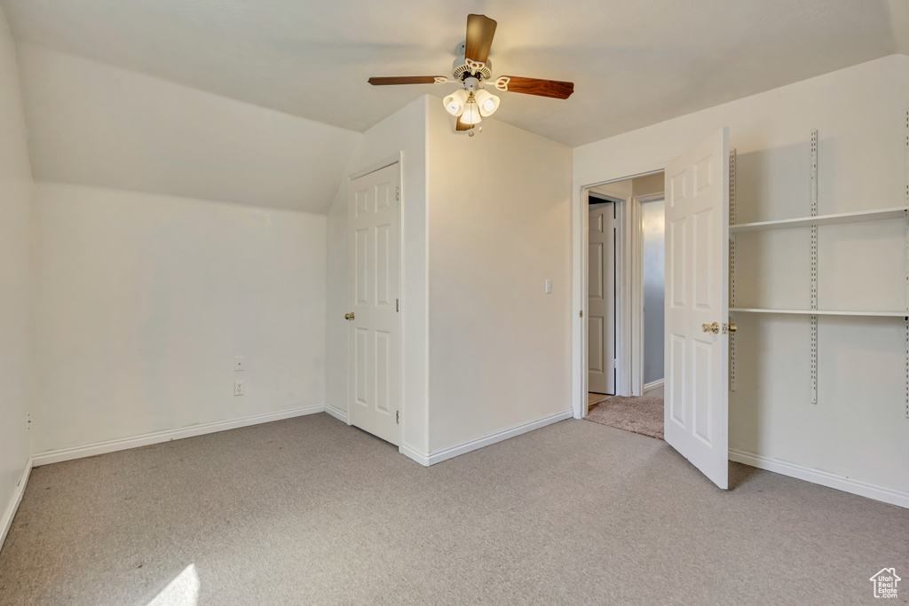 Unfurnished bedroom with carpet, vaulted ceiling, ceiling fan, and baseboards