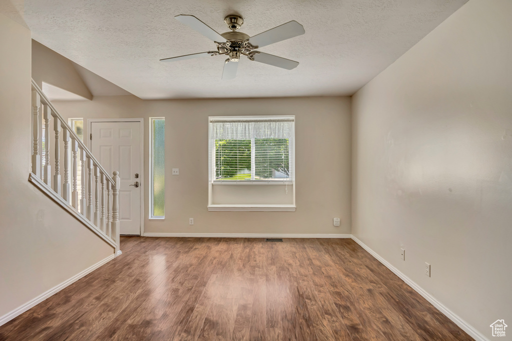 Entrance foyer with wood finished floors, baseboards, stairway, and a textured ceiling
