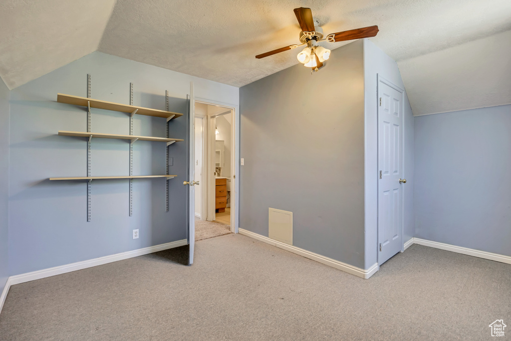 Unfurnished bedroom featuring vaulted ceiling, carpet, baseboards, and a ceiling fan