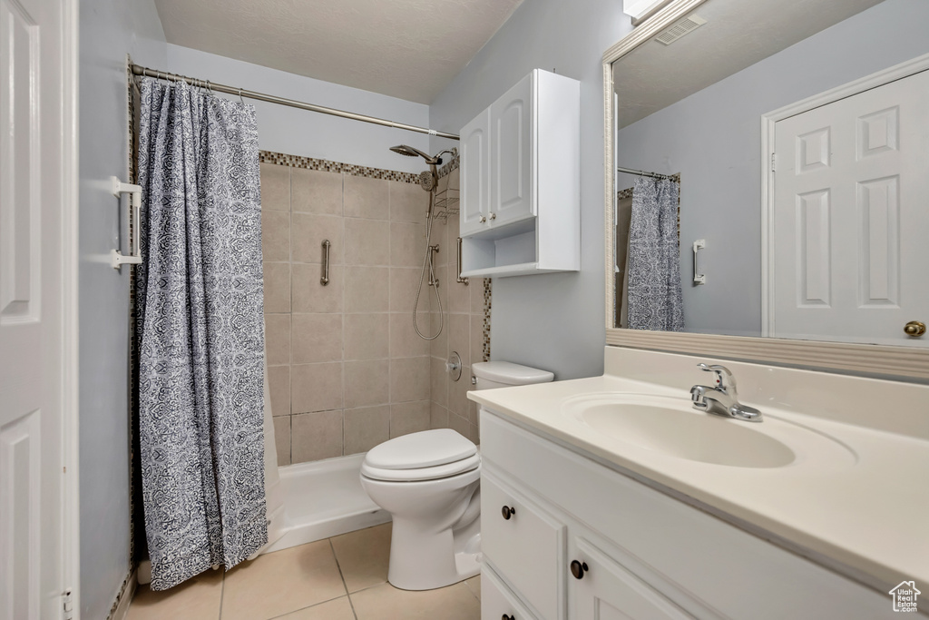 Full bath with vanity, toilet, tile patterned flooring, and tiled shower
