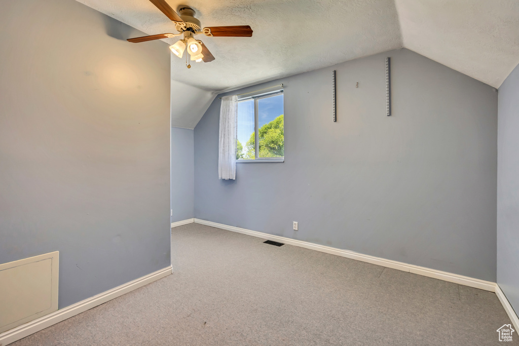 Bonus room with lofted ceiling, a ceiling fan, baseboards, and carpet floors
