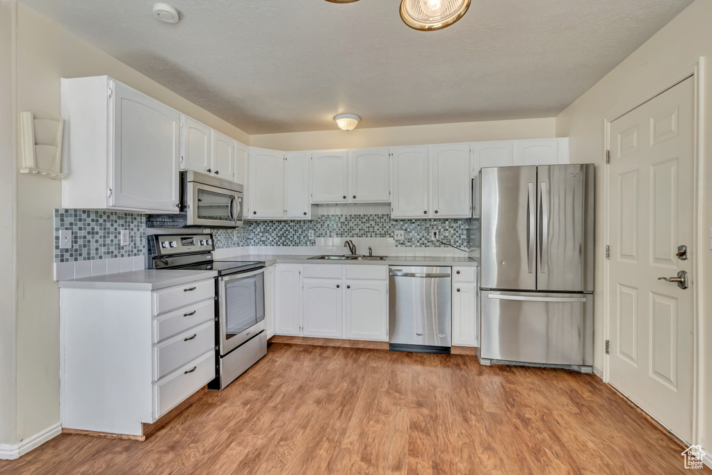 Kitchen featuring appliances with stainless steel finishes, a sink, light countertops, and white cabinets