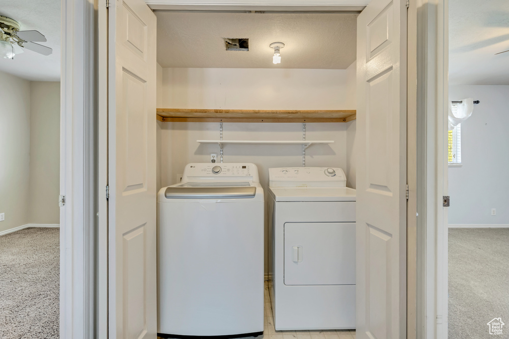 Laundry room with separate washer and dryer, a ceiling fan, light carpet, and baseboards