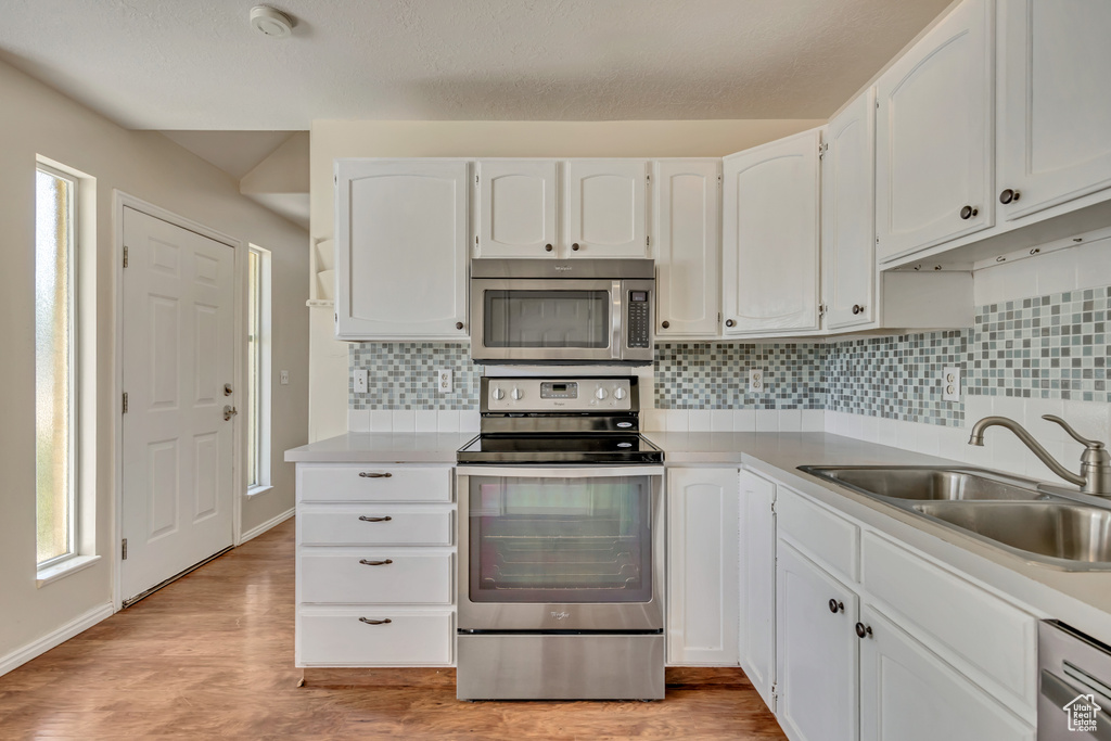 Kitchen featuring appliances with stainless steel finishes, a sink, plenty of natural light, and white cabinetry