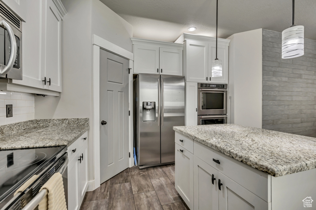 Kitchen featuring appliances with stainless steel finishes, dark wood finished floors, white cabinetry, tasteful backsplash, and recessed lighting