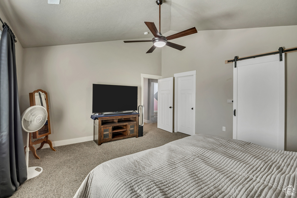 Bedroom featuring a barn door, carpet flooring, baseboards, a ceiling fan, and high vaulted ceiling