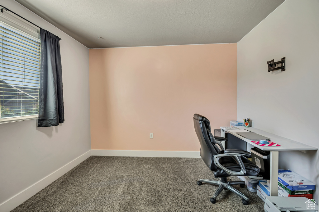 Unfurnished office with dark carpet and baseboards