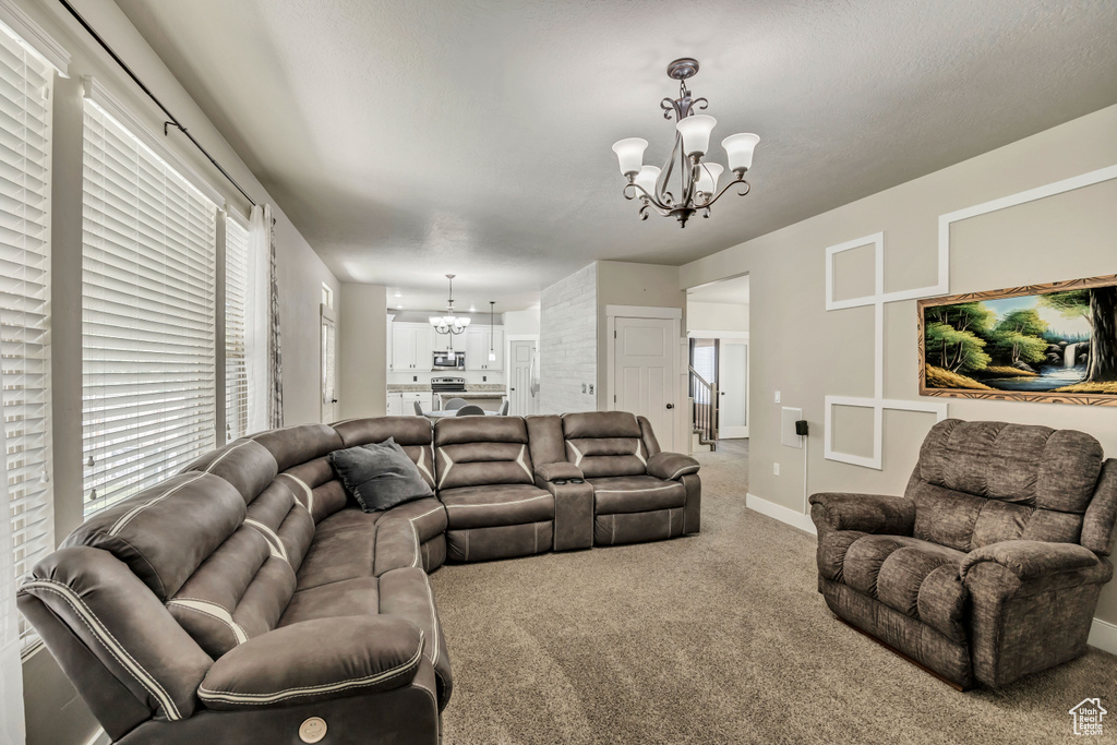 Carpeted living room with a chandelier, healthy amount of natural light, and baseboards