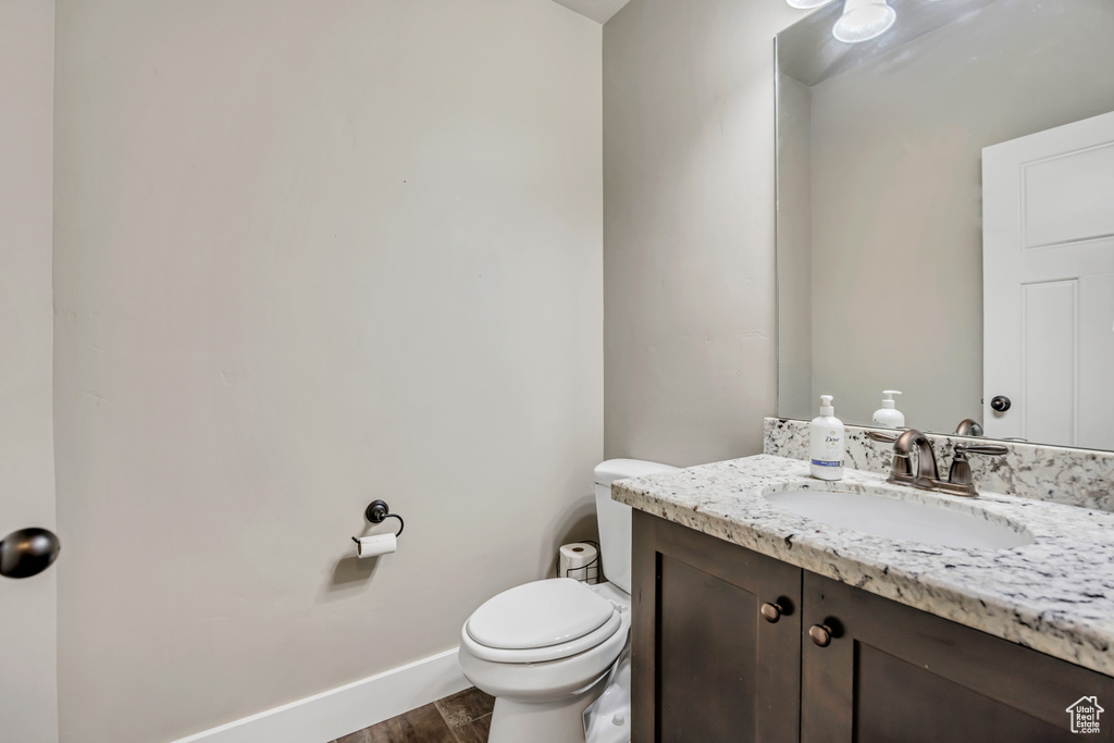 Bathroom featuring vanity, toilet, baseboards, and wood finished floors