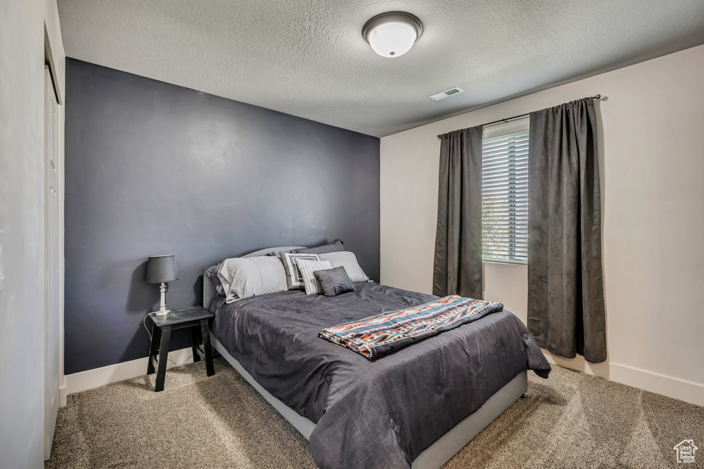 Bedroom featuring carpet, a textured ceiling, and baseboards