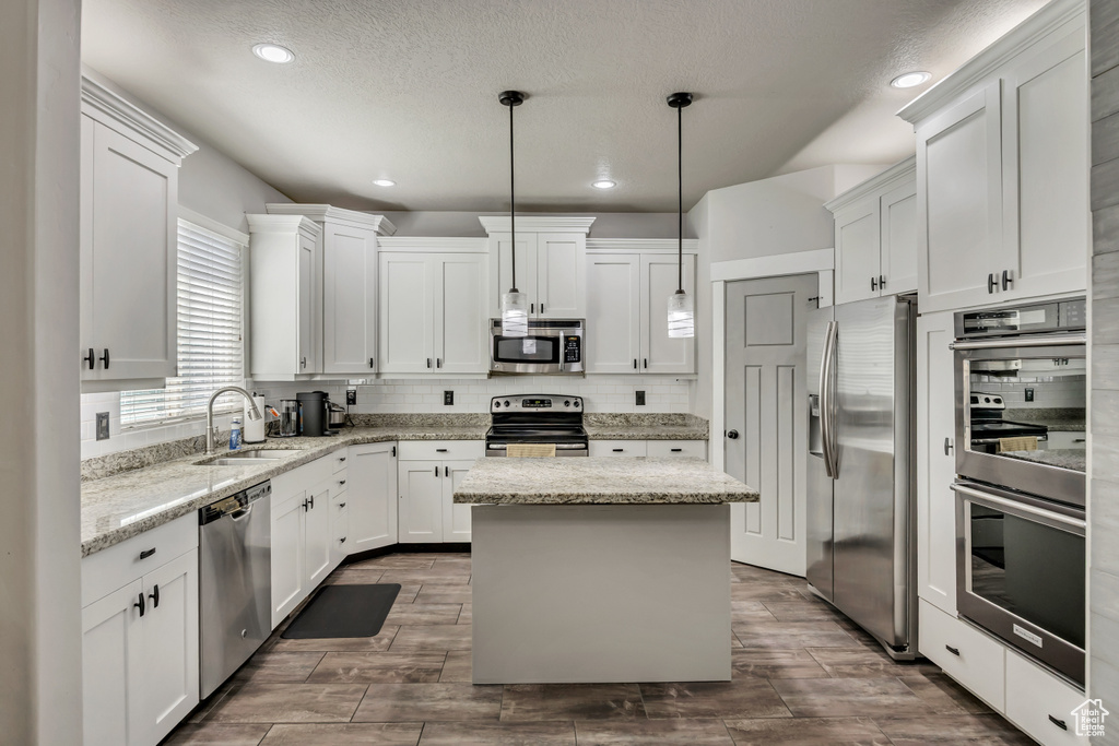 Kitchen featuring stainless steel appliances, a sink, white cabinets, tasteful backsplash, and recessed lighting