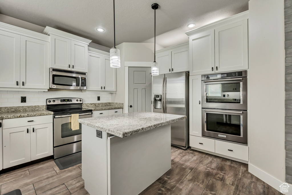 Kitchen featuring stainless steel appliances, recessed lighting, a kitchen island, decorative backsplash, and dark wood-style floors