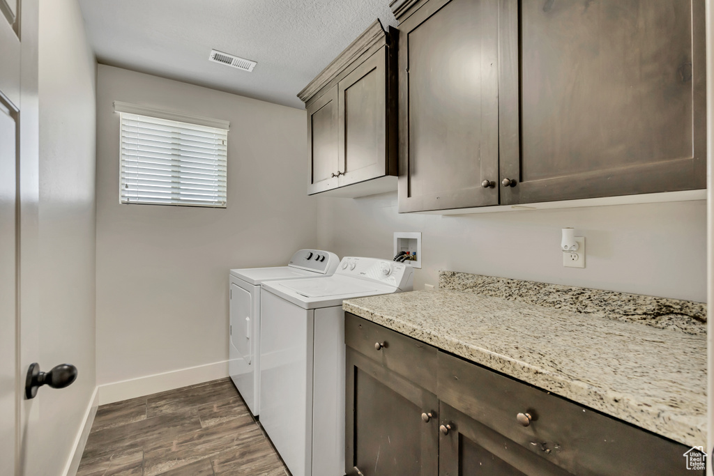 Laundry area featuring cabinet space, dark wood-style floors, washer and clothes dryer, baseboards, and a textured ceiling