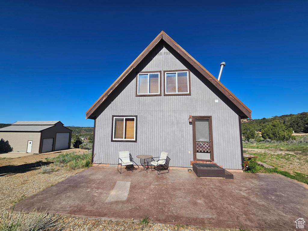 Rear view of house with an outbuilding and a patio area