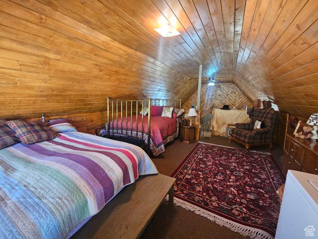 Bedroom with vaulted ceiling, wood walls, wood ceiling, and carpet