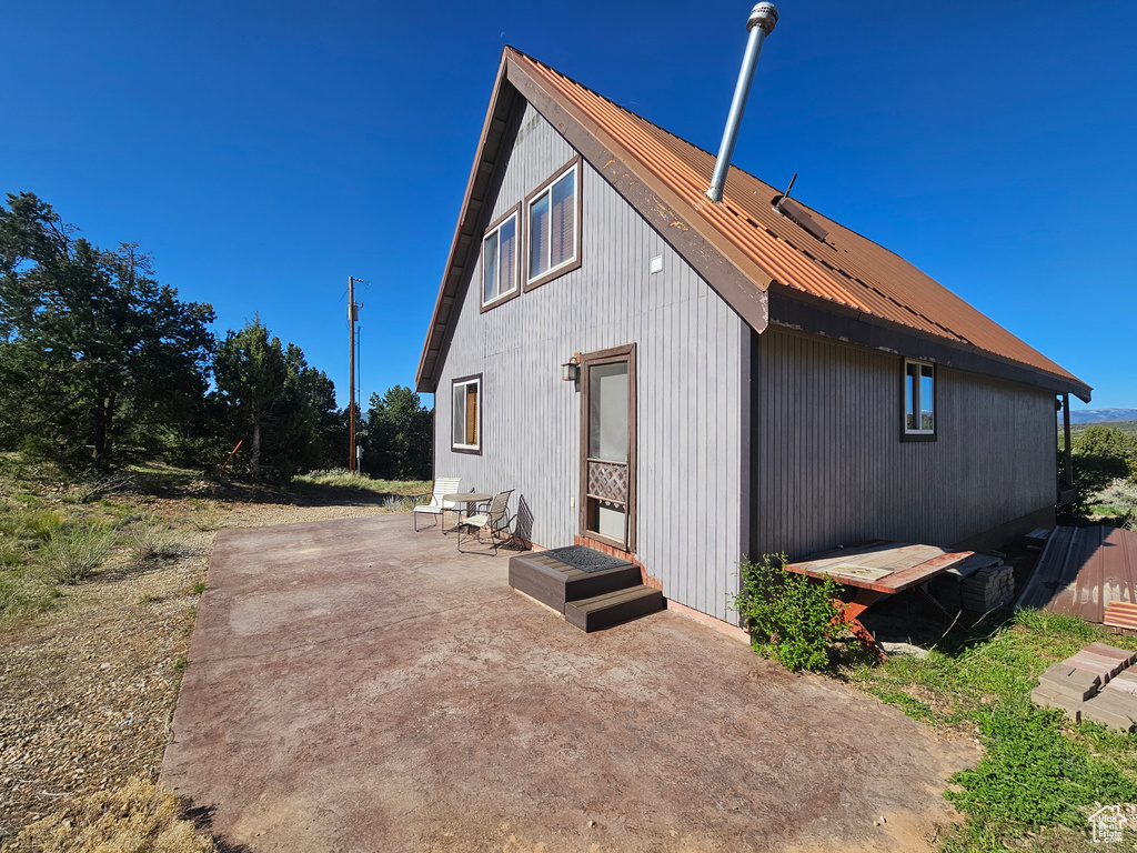 View of side of property with a patio area and metal roof