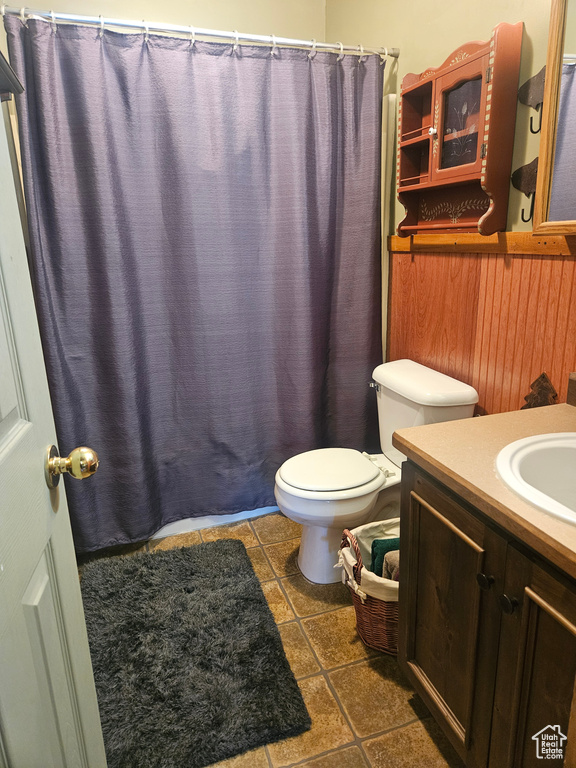 Bathroom with toilet, vanity, a shower with shower curtain, and tile patterned flooring