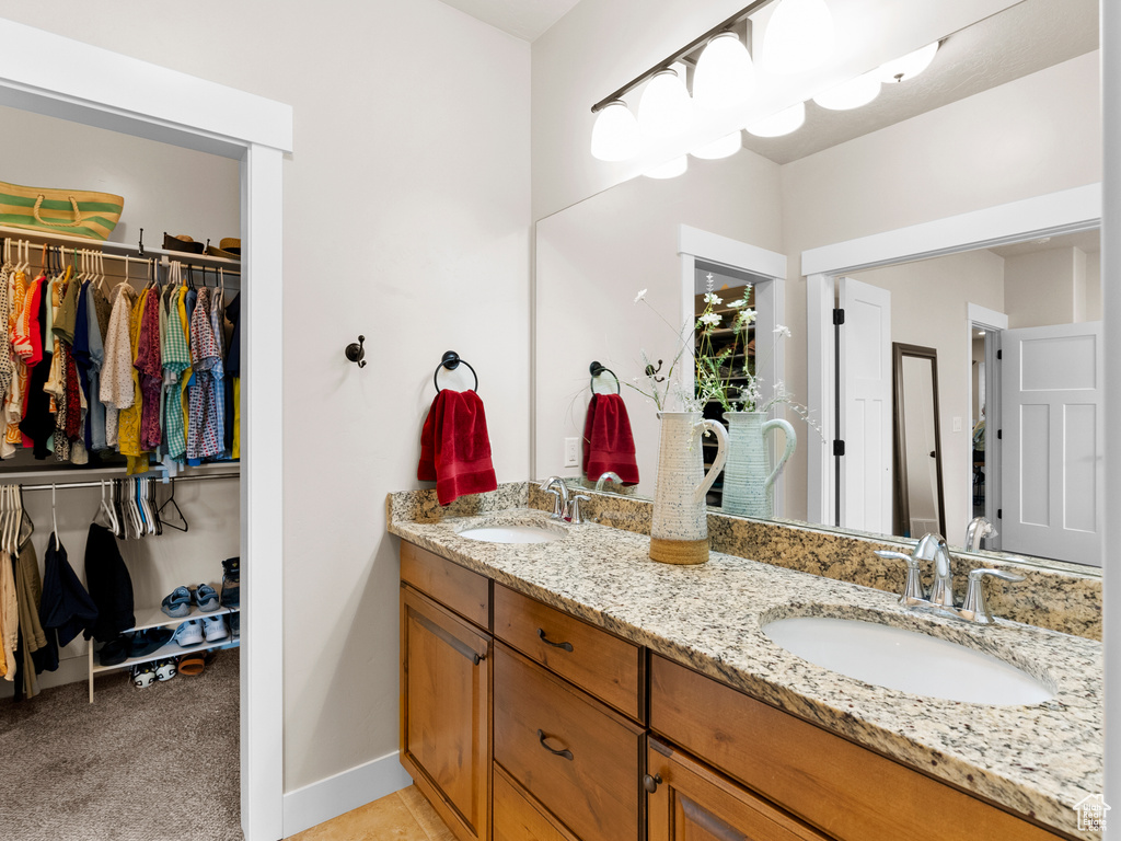 Full bath with double vanity, a spacious closet, and baseboards