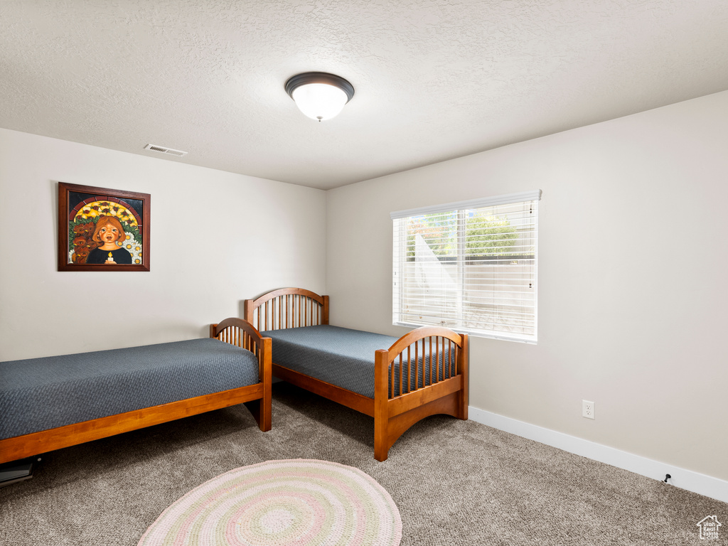 Carpeted bedroom with a textured ceiling and baseboards