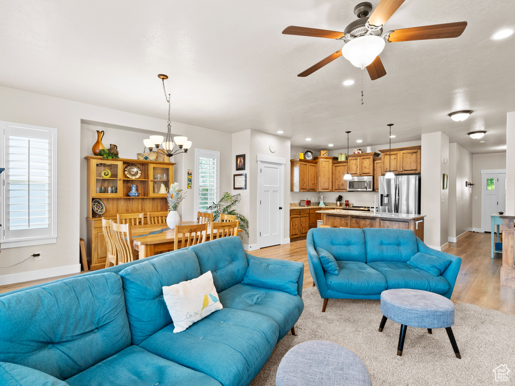 Living area featuring a chandelier, light wood-style floors, baseboards, recessed lighting, and ceiling fan