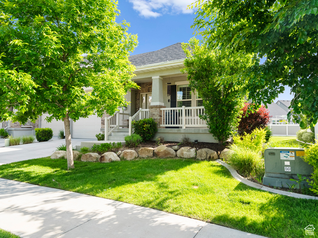 Obstructed view of property with a porch, a front lawn, an attached garage, concrete driveway, and roof with shingles