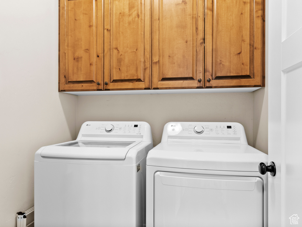 Laundry area featuring separate washer and dryer and cabinet space