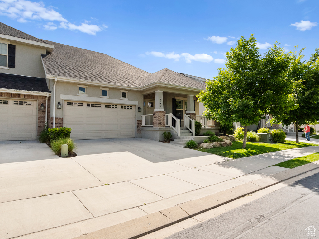 View of front of property with stucco siding, concrete driveway, brick siding, an attached garage, and roof with shingles