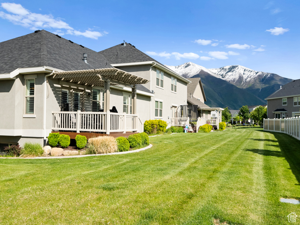 Back of property with a pergola, a mountain view, stucco siding, roof with shingles, and a residential view