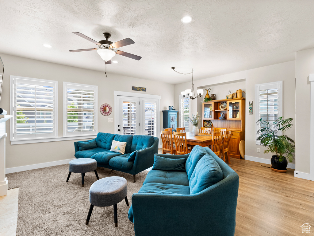 Living room featuring baseboards, a ceiling fan, a chandelier, a textured ceiling, and recessed lighting