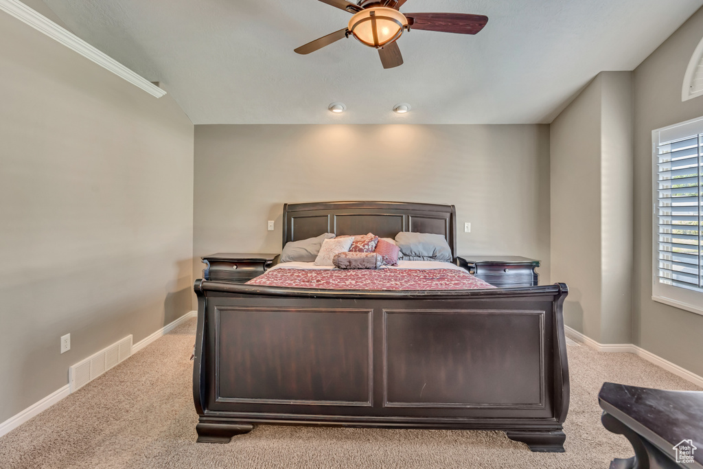 Bedroom with light colored carpet, baseboards, and a ceiling fan